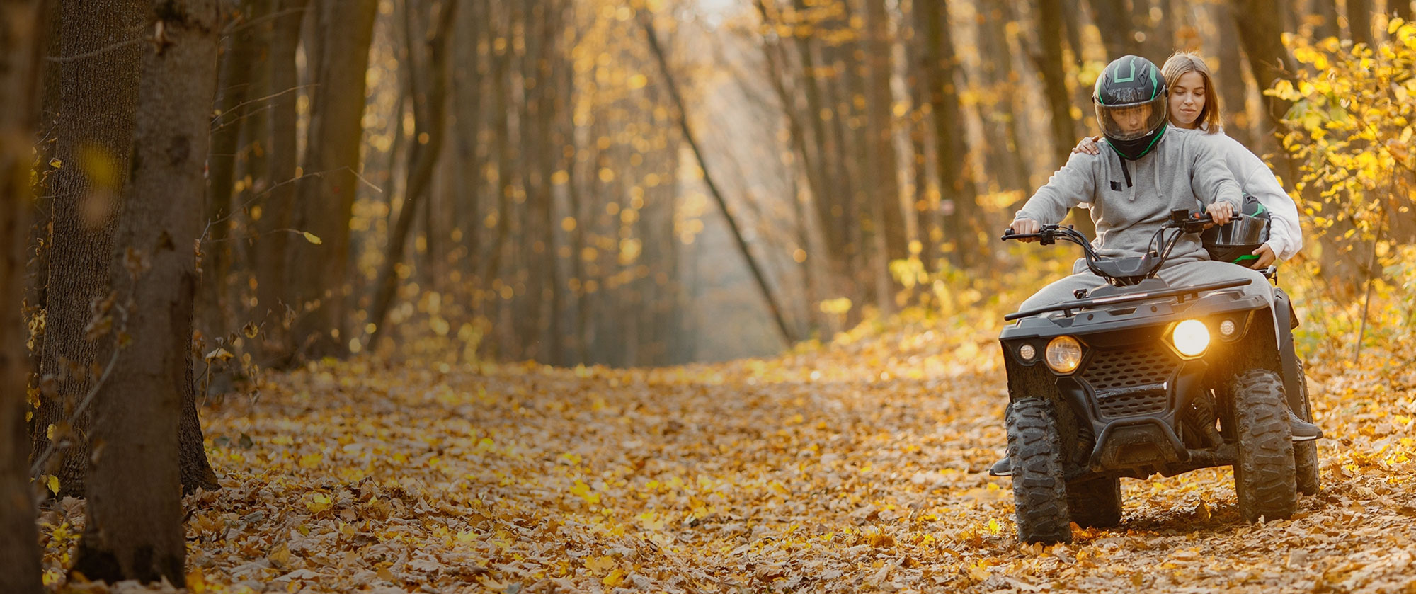 ATV riders on trail through autumn forest